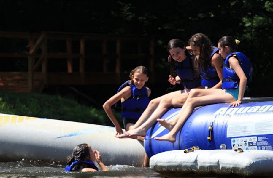 Kids playing on inflatables on a lake.