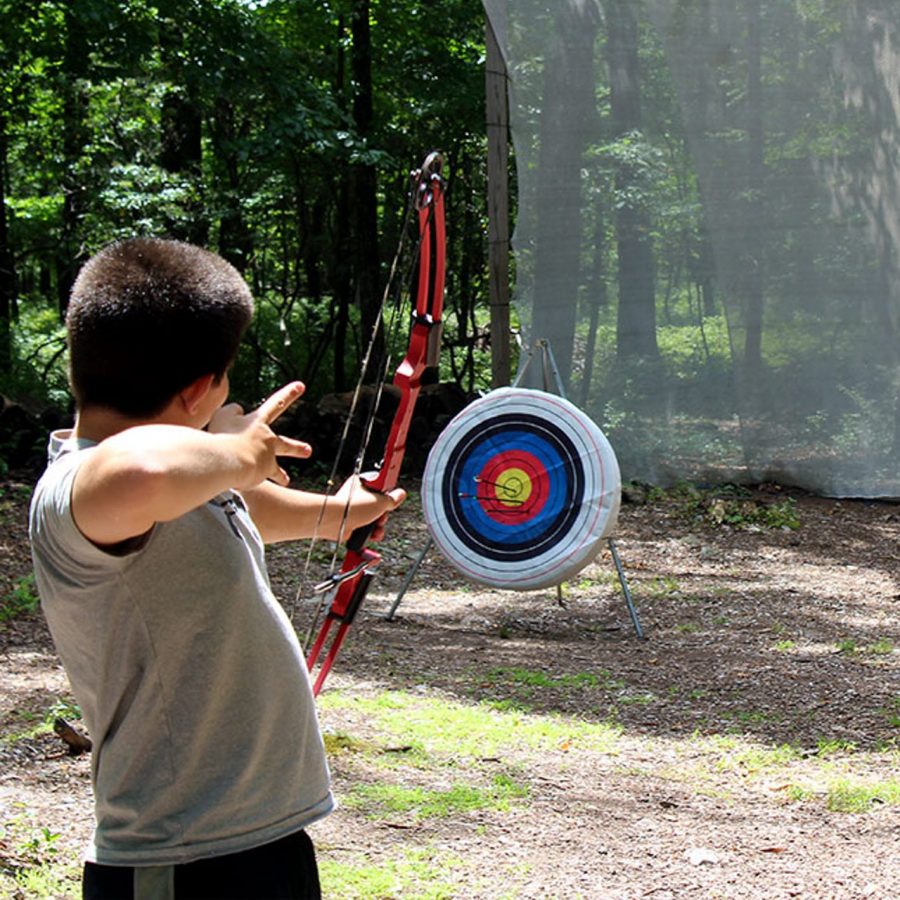 Boys shooting archery arrow at target