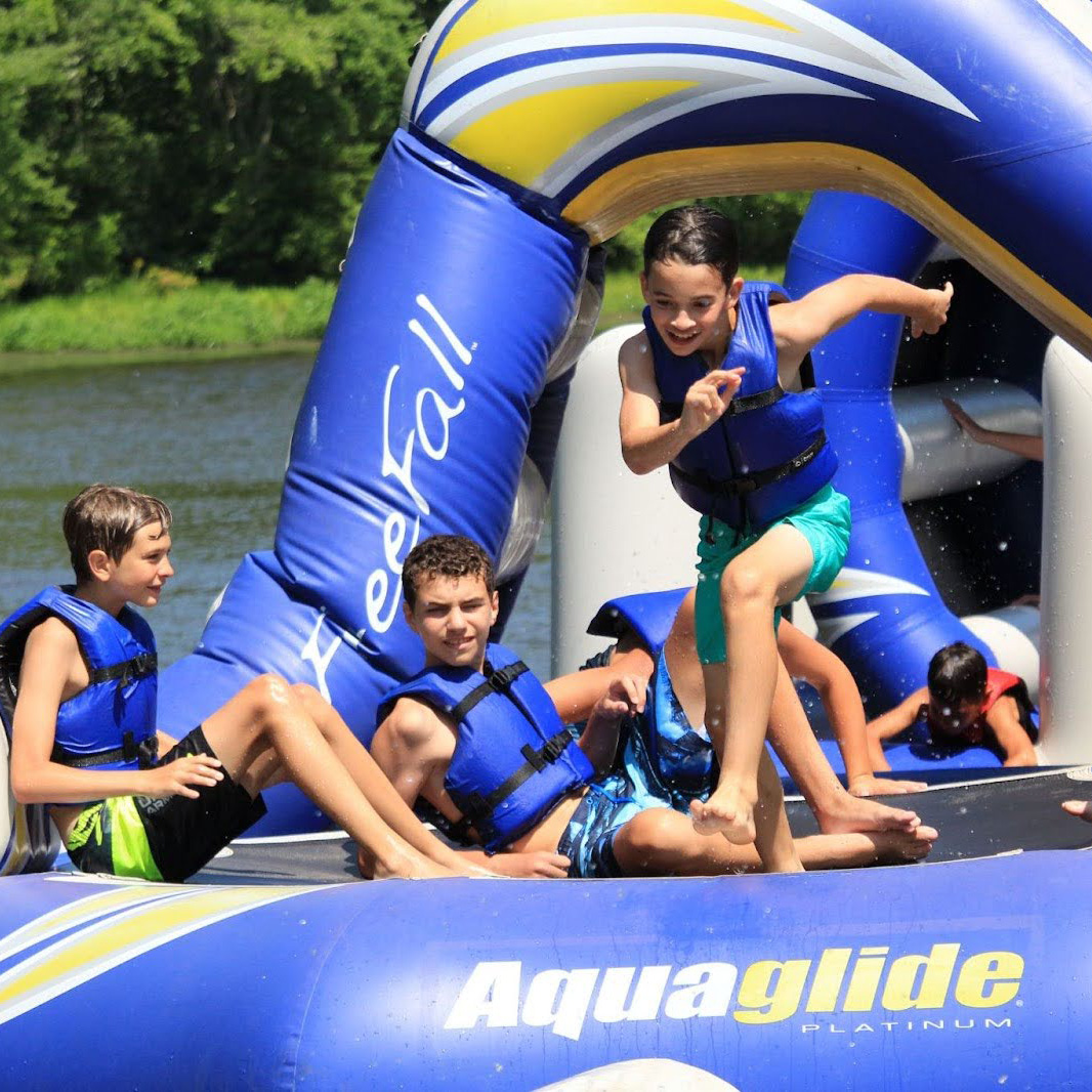 boys jumping off a lake inflatable.